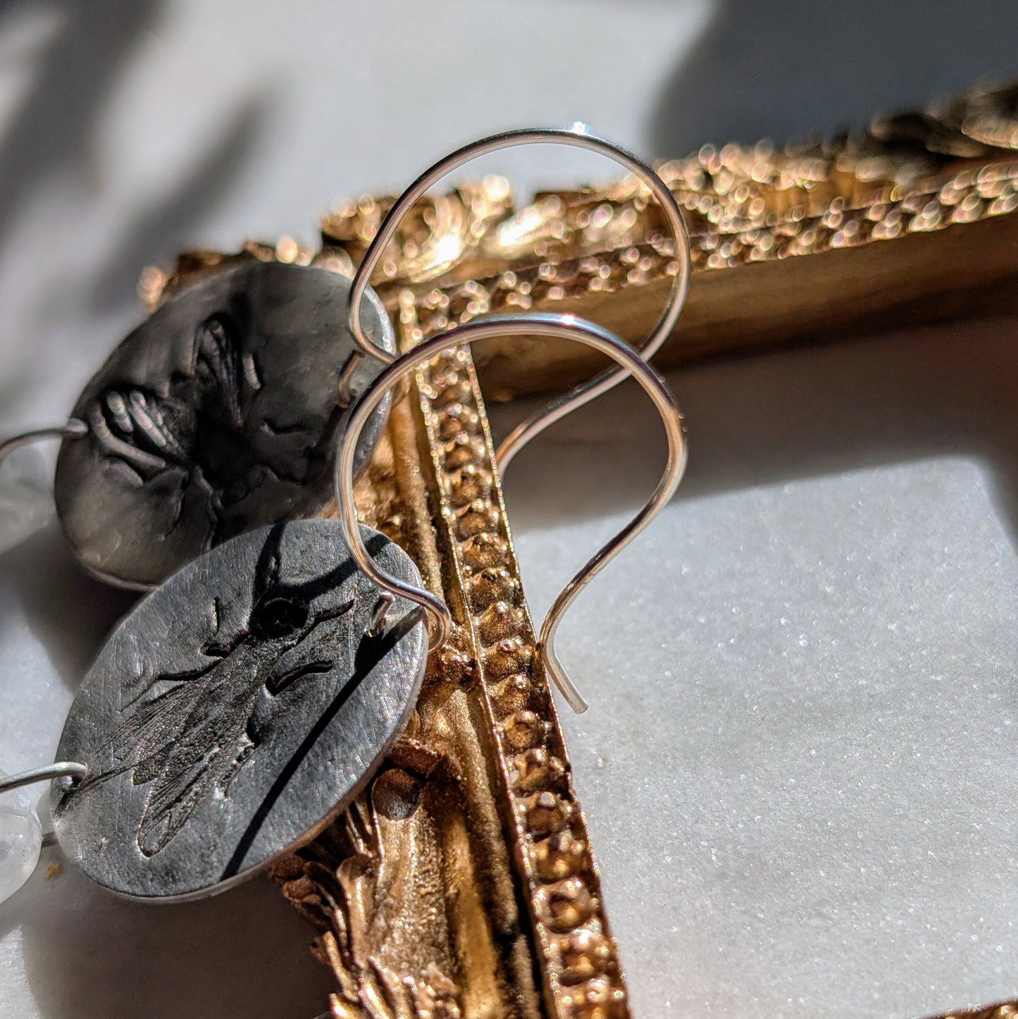 Handgefertigte Ohrringe aus Silber mit feinem Insektenrelief und Mondstein