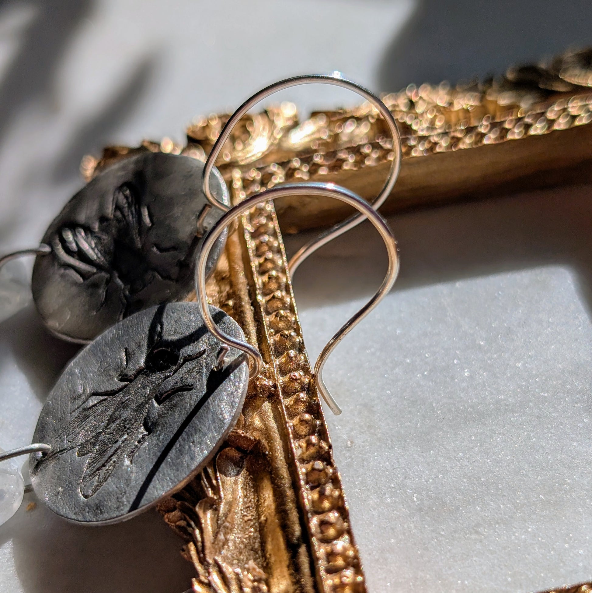 Handgefertigte Ohrringe aus Silber mit feinem Insektenrelief und Mondstein
